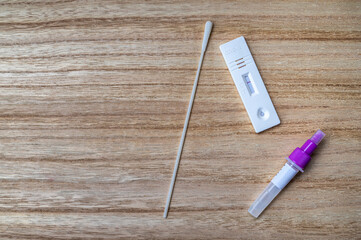 Covid 19 Schnelltest mit Abstrichstäbchen, Röhrchen und Teststreifen auf hölzernen Hintergrund
