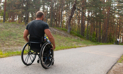 Obraz premium Young disabled athlete in a walking pine park in a wheelchair