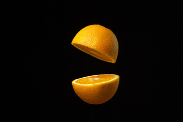Orange cut in half in the air against a dark background. Sliced orange on a black background....