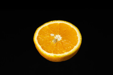 Half an orange on a dark background. Sliced orange on a black background. Creative photography of orange