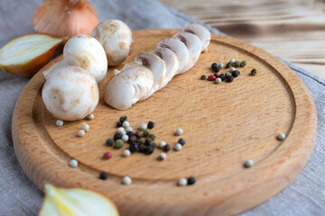 halves of champignons, onions, peppers on a wooden cutting board. Mushrooms as vegetable protein, raw food diet, vegetarianism. View from above.