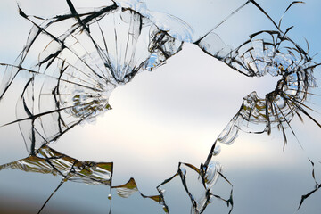 Broken window glass on a background of blue sky