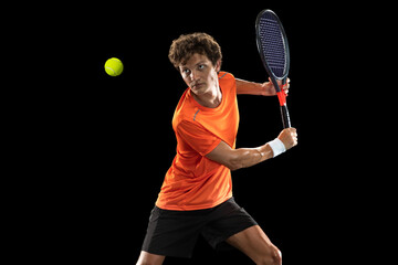 Young Caucasian man, professional tennis player isolated on black background.