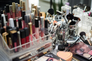 Close-up picture of workplace with make-up tools on table in beauty salon. Professional lipsticks and brushes for work of make-up artist. Work process in beauty studio.