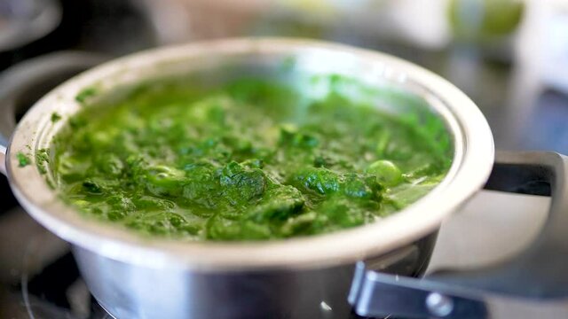 Blattspinat wird in der K&uuml;che im Topf gekocht. Vegetarisches Essen wird zubereitet.  4K 10 Bit 4:2:2
