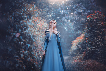 Beautiful fantasy woman elven goddess walks in spring nature forest. Long creative vintage blue dress, sleeves. Blond hair fluttering in motion. Fairy cute face. Art Girl elf princess fashion model. - obrazy, fototapety, plakaty