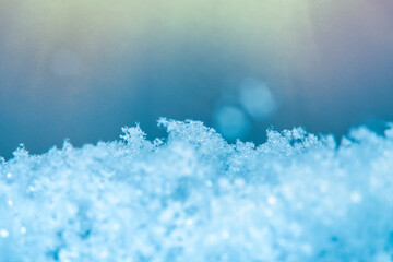 Background with close-up of snow under strong magnification with bright sunlight. Slightly melted snow with sharp edges in soft focus.