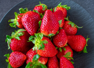 Strawberries on a dark plate from above
