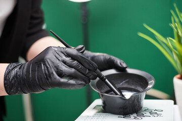 Close-up picture of hairdresser's tools in female hands with black gloves. Process of mixing hair...
