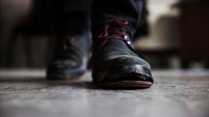 Close up front central perspective image of a pair of nubuk boots, one of which has a detached sole at the tip.