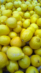 Yellow fresh lemons background. Fruits on supermarket shelves. Farmers market. Retail industry. Discount. Grocery shopping. Healthy eating. Greengrocer. Natural food. Store. Vertical view. Citrus