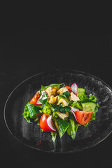 Salad with cucumber, tomato, red onion, pepper, parsley and Feta cheese on black background