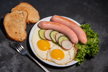 Two fried eggs and sausages, lettuce, cucumber and radish slices on a white plate, toast. Scrambled eggs. Breakfast. Healthy eating. Close-up