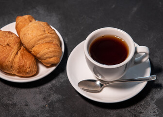 Tea or coffee on a saucer in a white cup with croissants. Breakfast. Close-up. Selective focus.
