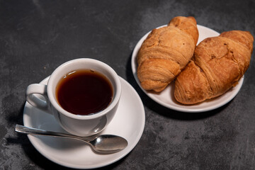 Tea or coffee on a saucer in a white cup with croissants. Breakfast. Close-up. Selective focus.