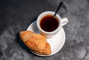 Tea or coffee on a saucer in a white cup with croissants. Breakfast. Close-up. Selective focus.