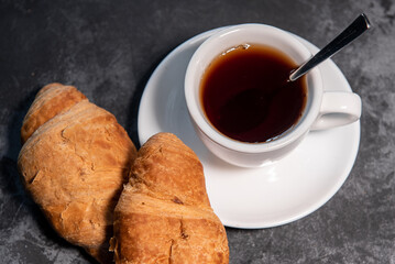 Tea or coffee on a saucer in a white cup with croissants. Breakfast. Close-up. Selective focus.