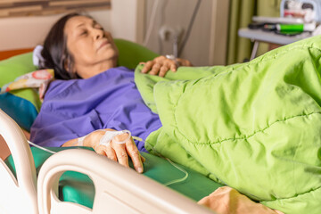 Senior patient hand with injection Saline lying in the hospital bed.