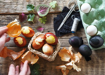 The process of preparing for the Easter holiday. Senior woman's hands show Easter eggs.Easter background with eggs and onion peel.
