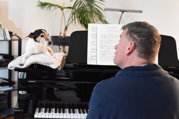 Mann spielt Klavier mit Hund