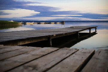 wooden old pier on the lake on the background of a summer sunset