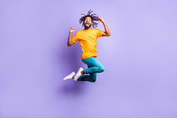 Fototapeta na wymiar Full size profile photo of nice optimistic brunette hairdo guy jump wear orange t-shirt pants isolated on lilac color background