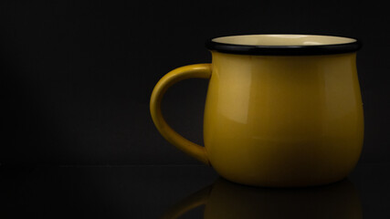 Studio side shot of a yellow mug isolated on a black background © Cristian Muñoz Gallardo/Wirestock