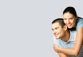 Portrait of standing close embracing couple in blue casual clothing, love studio concept, grey color background. Young brunette man and woman posing together. Copy space area for slogan or text.