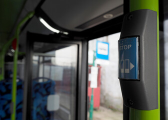 stop button in an empty bus with open doors. inside a public bus in europe