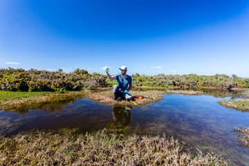 Scientist measuring environmental water quality parameters in a wetland.