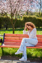 Portrait of a woman sitting on a bench in the park on a beautiful spring day.