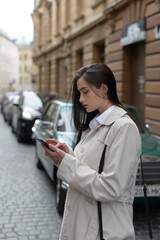 A woman on the street uses a mobile phone. online shopping. use of mobile applications.