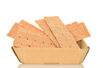 Light brown multi-grain rye crispbreads in a paper dish, close-up, isolated on white.