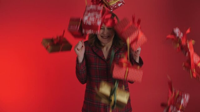 Fulfillment of desires. Gifts fall on the woman from above. The Girl receives many gifts. Prize, draw. Isolated on red background.