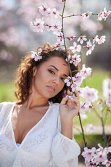 spring portrait of a beautiful woman with curly hair next to tree flowers