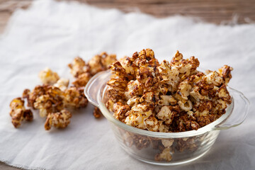 Chocolate popcorn in glass bowl on wooden table background
