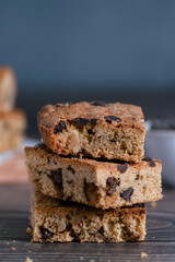 Close up of pile of delicious blondie (brownie) on a dark background. Homemade biscuit with chocolate chips. Vertical..