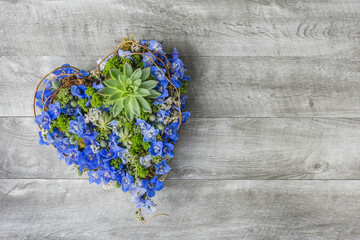 Heart shape of blue flowers on a grey wooden background - Wood Table flat lay - Sympathy flowers - Romantic flowers