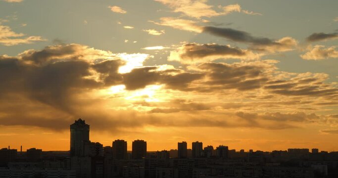City landscape at sunset. Silhouette of residential buildings in the rays of the orange sun.