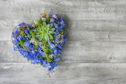 Heart shape of blue flowers on a grey wooden background - Wood Table flat lay - Sympathy flowers - Romantic flowers - Powered by Adobe