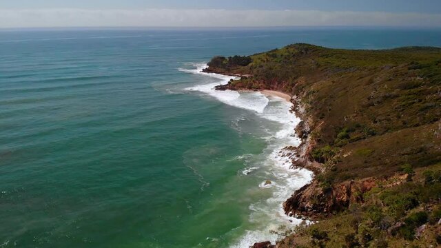 Aerial drone view over waves hitting the coast of Evans Head, in sunny Australia