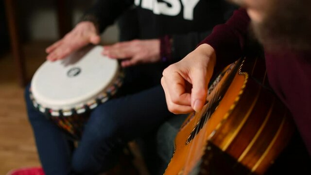 Creating a new album. The man bangs the jambe drum with his hands. The hand of a musician plays the guitar. Musicians hands make music. 