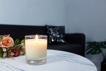 luxury aroma lighting aromatic scented candle glass displayed on white marble table to creat romantic and relax ambient on valentine day with background of grey sofa in living room