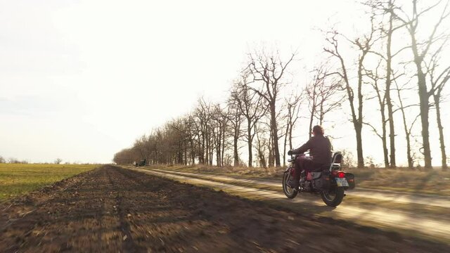 Following A Red Motorbike Riding Through Dirt Roads At The Countryside. Bright Autumn Sun At The Fields A Good Path For Young Biker, To Feel A Freedom Spirit