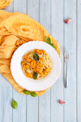 Pasta, spaghetti with yellow tomato in white plate. Blue background. Top view. Close up.