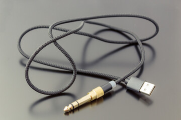 Microphone cable with USB connector, on a dark background.