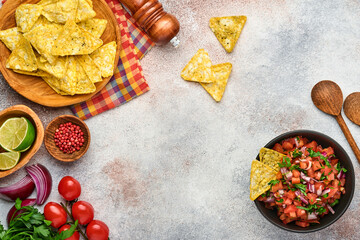Traditional Mexican tomato sauce salsa with nachos and ingredients tomatoes, chile, garlic, onion on light slate stone background. Concept of Latin American and Mexican food. Mock up.