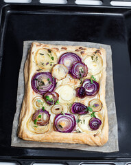 Freshly baked french onion tart on baking tray
