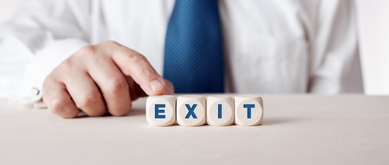 Businessman pressing his finger on the wooden cubes with the word exit.