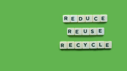 Top view of an alphabet of reduce, reuse and recycle on green background with copy space.